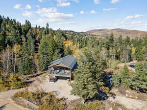 Aerial view of property and surrounding area with a heavily wooded area and a mountainous background