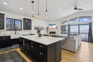 Kitchen featuring sink, hanging light fixtures, a center island, a fireplace, and a healthy amount of sunlight