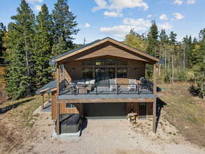 Back of property with driveway, a deck, a garage, and an outdoor hangout area