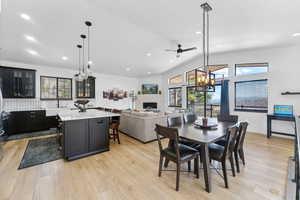 Kitchen with light hardwood / wood-style flooring, a kitchen breakfast bar, a fireplace, a kitchen island, and decorative light fixtures