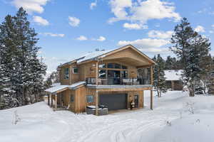 Snow covered back of property featuring a garage and a balcony