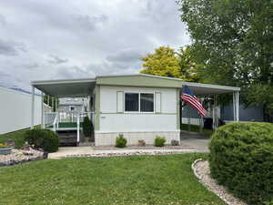 Manufactured / mobile home featuring a front lawn and a carport