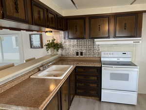 Kitchen with backsplash, dark brown cabinetry, light hardwood / wood-style floors, and white electric range