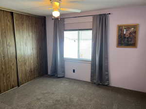 Carpeted empty room with wooden walls and ceiling fan