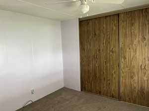 Unfurnished room with ceiling fan, carpet floors, and wood walls