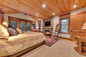 Bedroom with a stone fireplace, french doors, carpet flooring, and wood ceiling