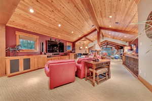 Living room featuring vaulted ceiling with beams, light carpet, and wooden ceiling