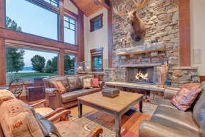 Living room with a stone fireplace, high vaulted ceiling, hardwood / wood-style flooring, and plenty of natural light