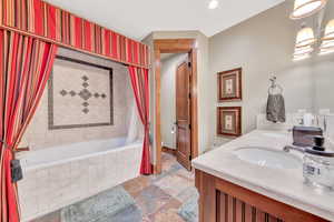 Bathroom featuring tile floors, tiled tub, and dual bowl vanity