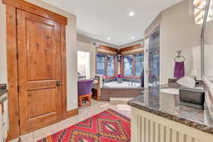 Bathroom with tile flooring, vanity, and a tub