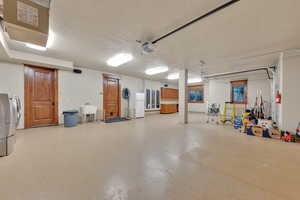 Garage with sink, a garage door opener, and independent washer and dryer