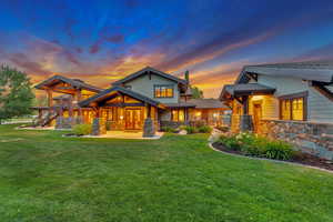 Back house at dusk featuring a lawn