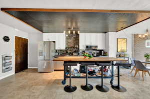 Kitchen featuring white cabinets, butcher block countertops, appliances with stainless steel finishes, and a chandelier