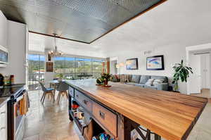 Kitchen featuring hanging light fixtures, appliances with stainless steel finishes, light tile flooring, and butcher block counters