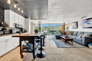 Interior space featuring an inviting chandelier, white cabinets, range with electric cooktop, and light tile floors