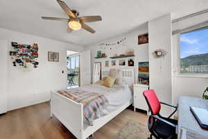 Bedroom featuring ceiling fan, hardwood / wood-style flooring, a textured ceiling, and access to outside