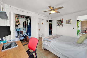 Bedroom with a textured ceiling, hardwood / wood-style floors, ensuite bath, a closet, and ceiling fan