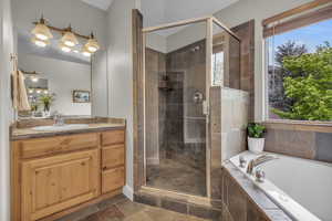 Bathroom with tile floors, a healthy amount of sunlight, shower with separate bathtub, and vanity