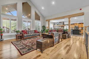 Living room with high vaulted ceiling, ornate columns, and light wood-type flooring