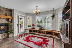 Interior space featuring dark tile flooring, a textured ceiling, a wealth of natural light, and a stone fireplace