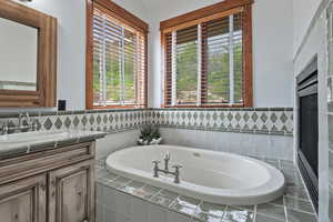 Bathroom featuring tiled tub and large vanity with lots of natural sunlight