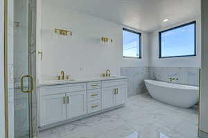 Bathroom featuring tile floors, dual vanity, independent shower and bath, and tile walls