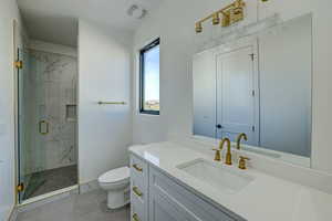 Bathroom with tile floors, vanity with extensive cabinet space, an enclosed shower, and toilet