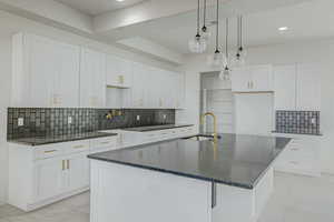 Kitchen featuring sink, white cabinets, and tasteful backsplash