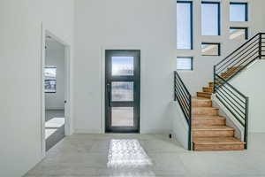 Carpeted entrance foyer with a towering ceiling and a wealth of natural light