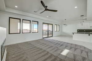 Unfurnished living room featuring ceiling fan and light carpet