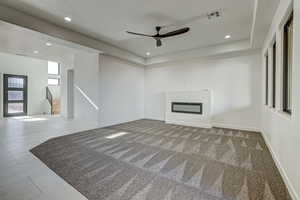 Unfurnished living room featuring carpet and ceiling fan