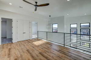 Empty room with ceiling fan and hardwood / wood-style flooring