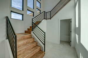 Stairway featuring a high ceiling and light tile flooring