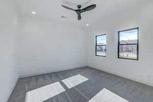 Unfurnished room featuring dark colored carpet and ceiling fan