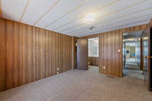 Carpeted empty room featuring wood walls and a textured ceiling