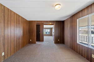 Unfurnished room with carpet floors and wood walls