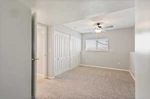 Carpeted empty room featuring ceiling fan and a textured ceiling