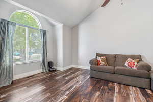 Living room featuring ceiling fan, dark hardwood / wood-style flooring, and lofted ceiling