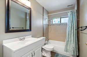 Full bathroom with tile flooring, vanity, toilet, and shower / tub combo with curtain