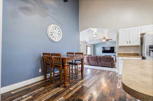 Dining space with dark hardwood / wood-style floors, high vaulted ceiling, and ceiling fan