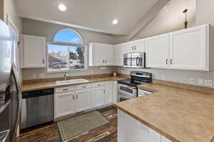 Kitchen featuring appliances with stainless steel finishes, sink, white cabinets, and plenty of natural light