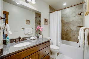 Full bathroom featuring shower / bathtub combination with curtain, vanity with extensive cabinet space, and toilet