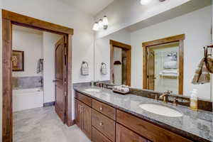 Bathroom featuring tile floors, vanity with extensive cabinet space, a washtub, and dual sinks