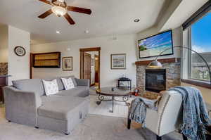 Carpeted living room featuring ceiling fan and a fireplace