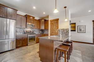 Kitchen featuring kitchen peninsula, stainless steel appliances, tasteful backsplash, and sink