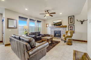 Living room featuring light tile floors, ceiling fan, and a fireplace