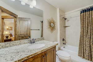 Full bathroom featuring tile floors, shower / bath combo with shower curtain, toilet, and vanity