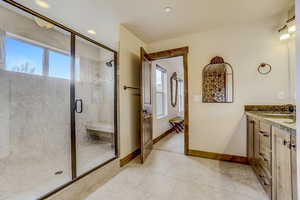 Bathroom featuring a shower with shower door, plenty of natural light, vanity, and tile floors