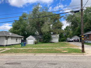 View of front of home with a garage, a front yard, and an outdoor structure