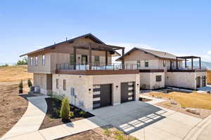 Contemporary house featuring a garage, a balcony, and cooling unit